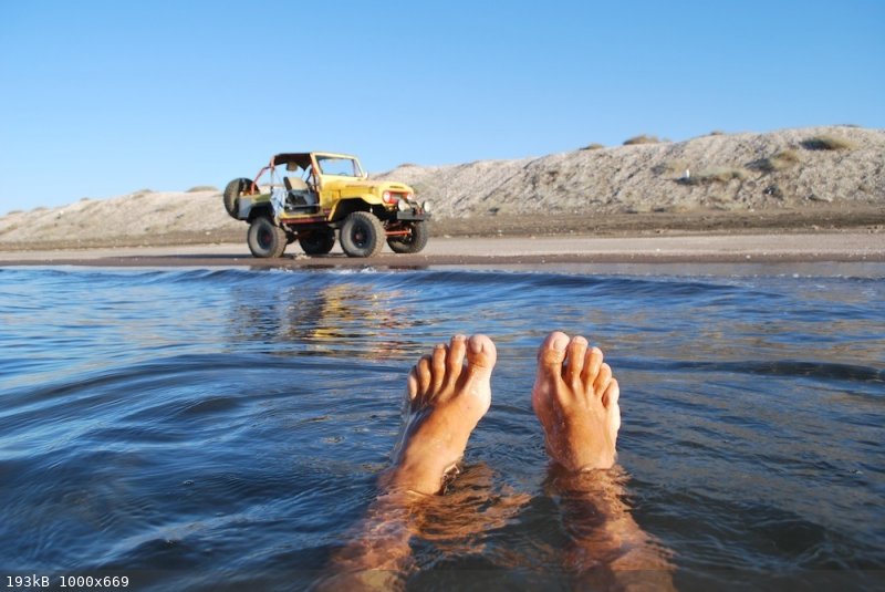 yellow toy on beach, feet in water.jpg - 193kB